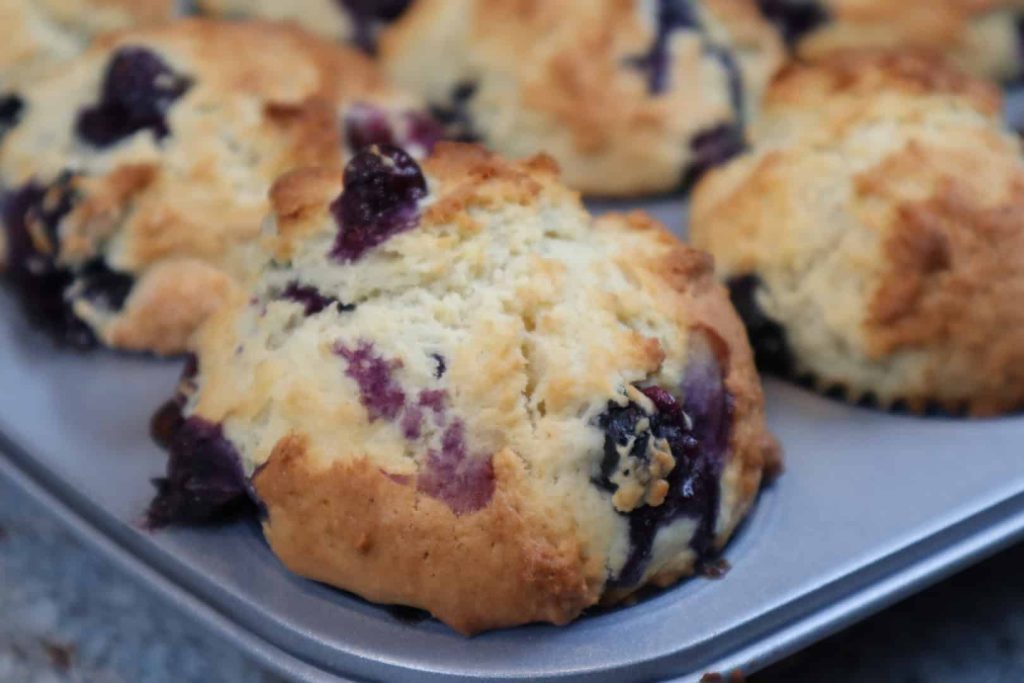 Close up of a freshly baked blueberry muffin still in the tin.