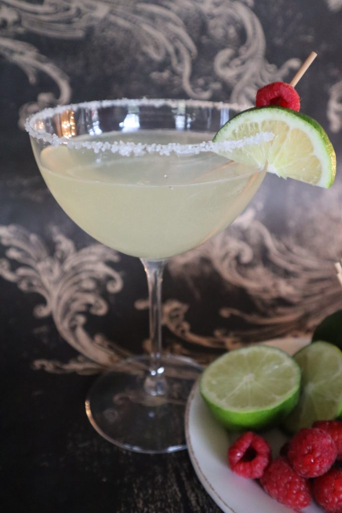 Raspberry margarita cocktails in glasses with lime and raspberry garnishes.