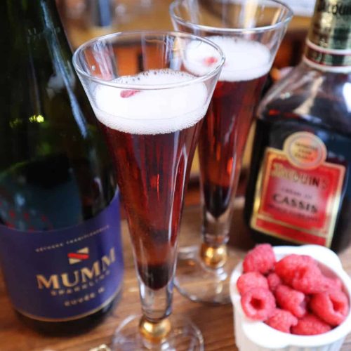 Two bubbling Kir Royale cocktails with raspberries.
